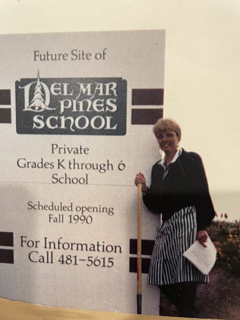 Del Mar Pines School founder Judy Panton stands next to a sign reading “Future Site of Del Mar Pines School, Private Grades K through 6 School”